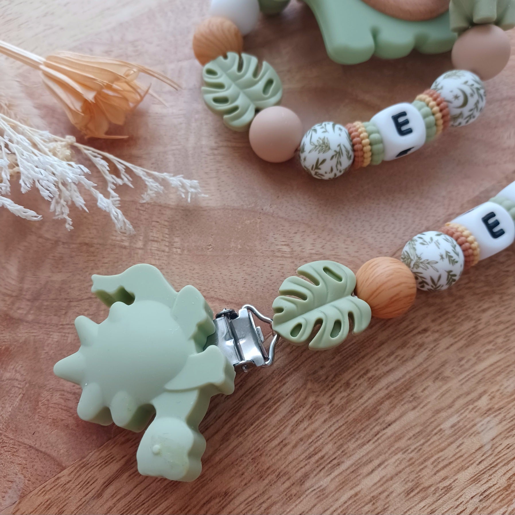 Ensemble attache tétine et anneau de dentition en silicone alimentaire sans BPA. 
Aux couleurs vert sauge et marron bois, entièrement personnalisable avec le prénom de votre bébé. Superbe cadeau de naissance.