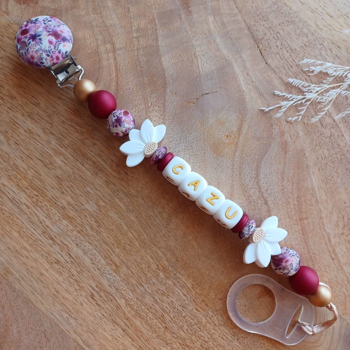 Attache tétine personnalisée en silicone avec prénom Cazu et fleurs blanches. Une attache tétine en silicone alimentaire sans bpa. Un anneau de dentition en silicone alimentaire, et cygne 