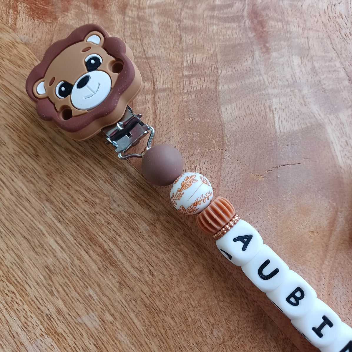 Attache tétine bébé personnalisée avec prénom. Design lion, couleurs douces, idéale pour un cadeau de naissance unique.