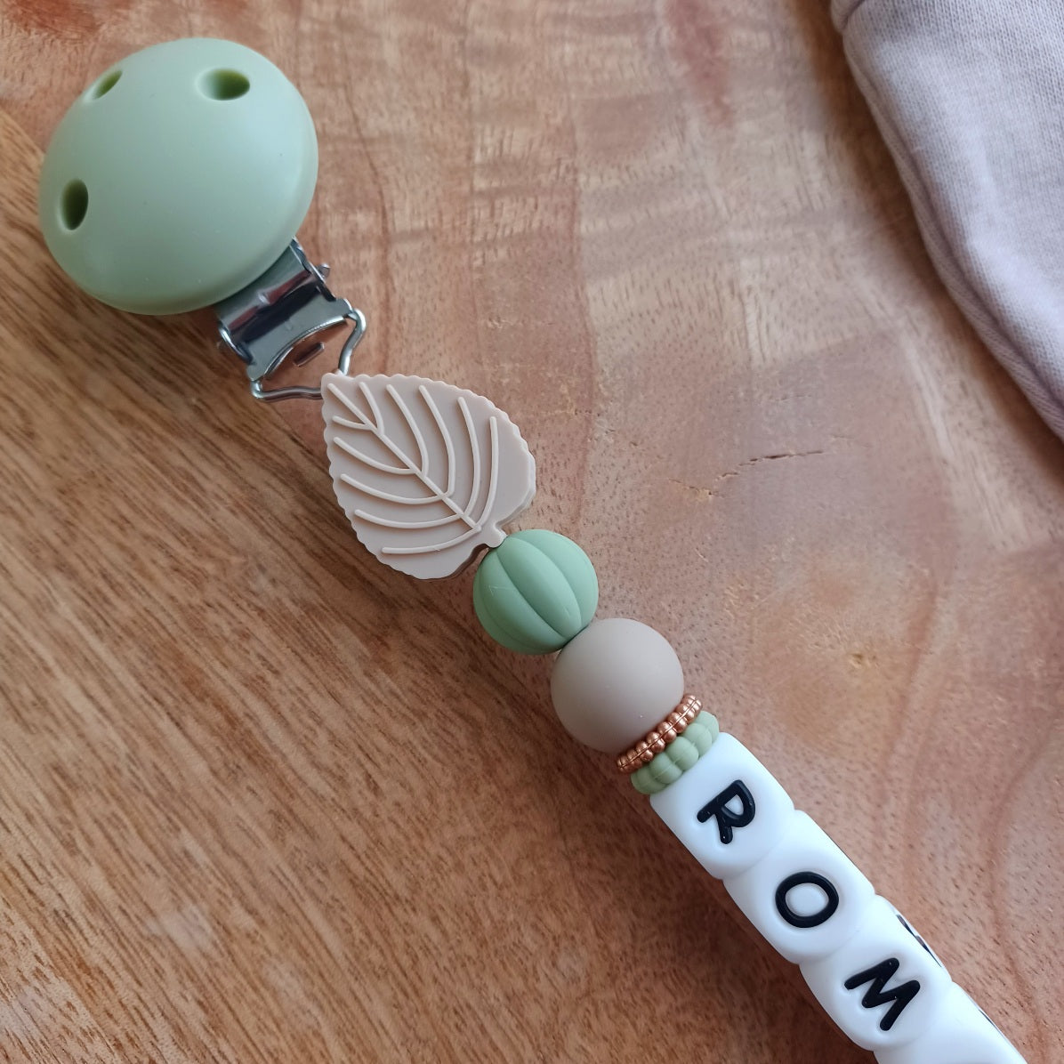 Attache tétine bébé personnalisée avec prénom. Design dinosaure, couleurs naturelles, idéale comme cadeau de naissance.