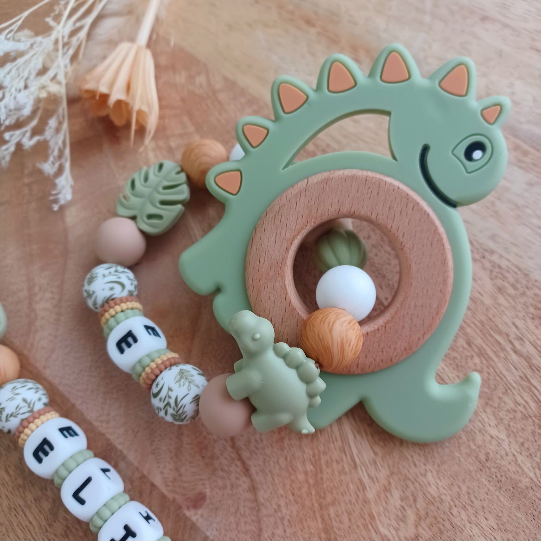 Ensemble attache tétine et anneau de dentition en silicone alimentaire sans BPA. 
Aux couleurs vert sauge et marron bois, entièrement personnalisable avec le prénom de votre bébé. Superbe cadeau de naissance.
