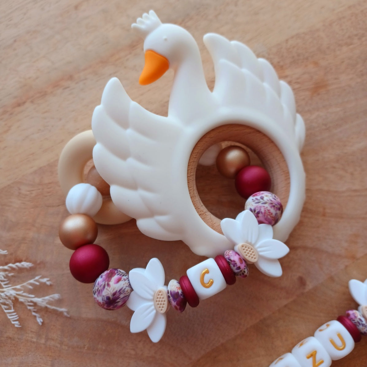 Attache tétine personnalisée en silicone avec prénom Cazu et fleurs blanches. Une attache tétine en silicone alimentaire sans bpa. Un anneau de dentition en silicone alimentaire, et cygne 