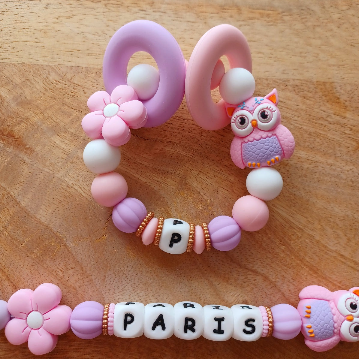 Attache tétine personnalisable en silicone alimentaire sans danger pour les bébés. Aux couleurs rose et lila, perles fleurs et hibou. Anneau de dentition avec des anneaux en silicone pour soulager les gencives des bébés. Superbe idée cadeau, babyshower, anniverssaire, baptême
