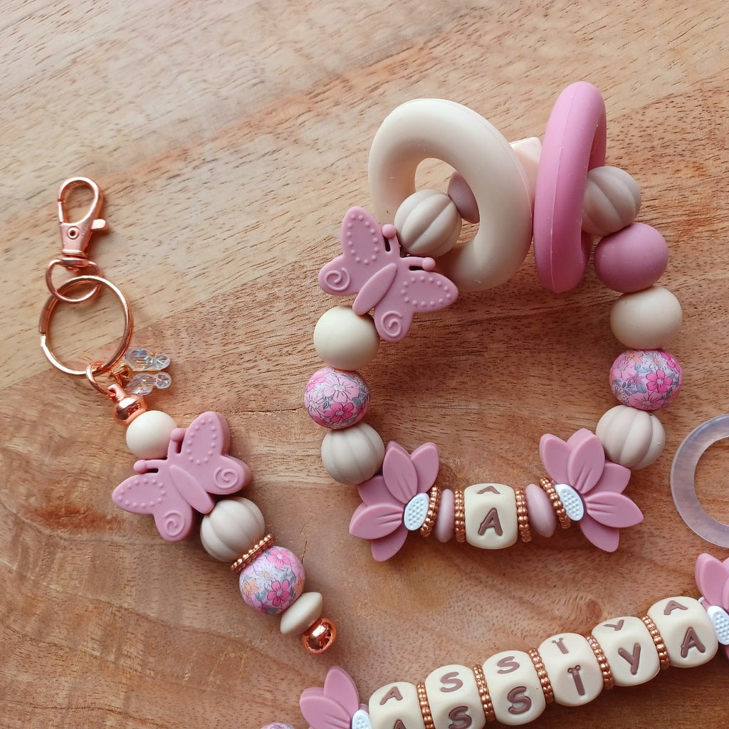 Attache tétine personnalisable avec le prénom de l'enfant, accompagné de son anneau de dentition assorti, en silicone alimentaire sans BPA. Aux couleurs vieux rose et beige