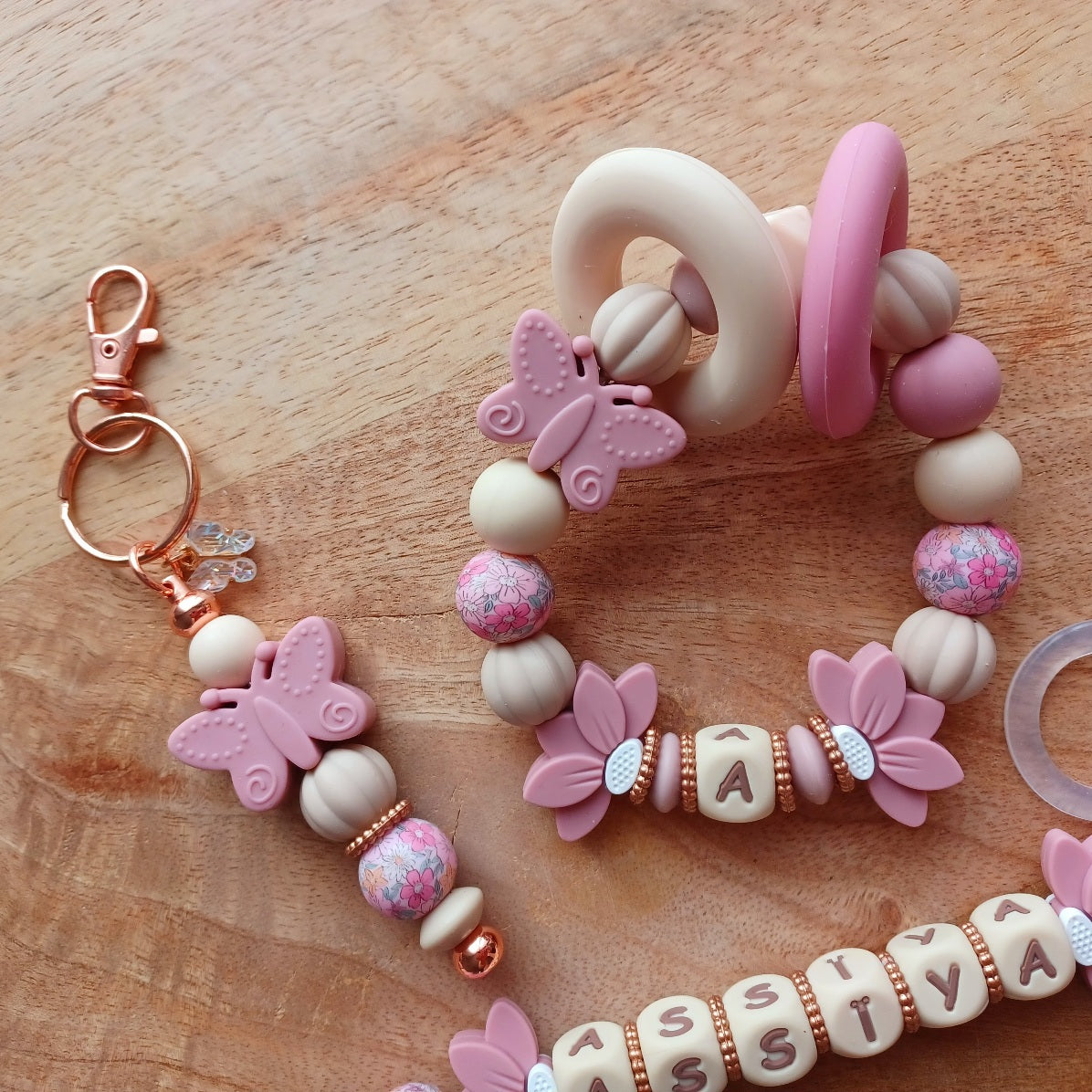 Attache tétine personnalisable avec le prénom de l'enfant, accompagné de son anneau de dentition assorti, en silicone alimentaire sans BPA. Aux couleurs vieux rose et beige