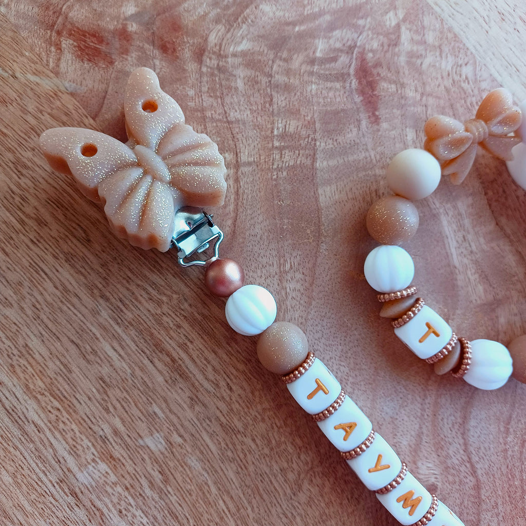Attache tétine personnalisée en silicone alimentaire. Perles en silicone blanc, beige, papillons. Anneau de dentition assorti, personnalisable avec le prénom du bébé. Cadeau de naissance.
