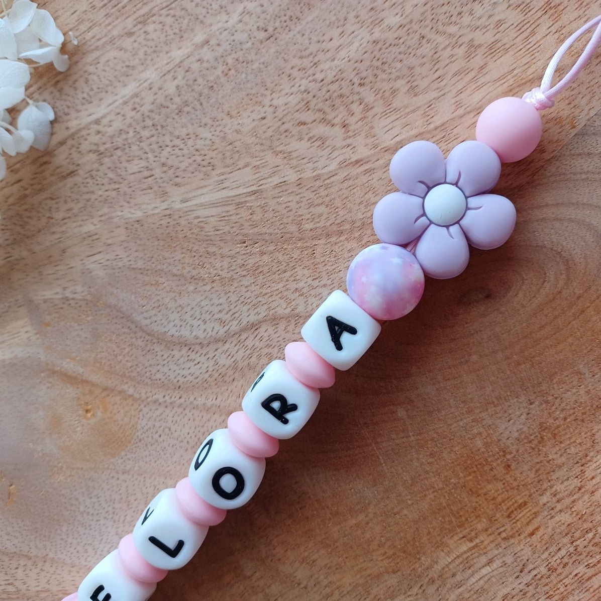 Attache tetine personnalisable, avec prénom du bébé ou enfant. Clip forme de fleur en silicone et acier inoxydable, perles du prénom en blanc et noir, perles rondes en lilas et rose pastel, perles de fleur . Cadeau de naissance