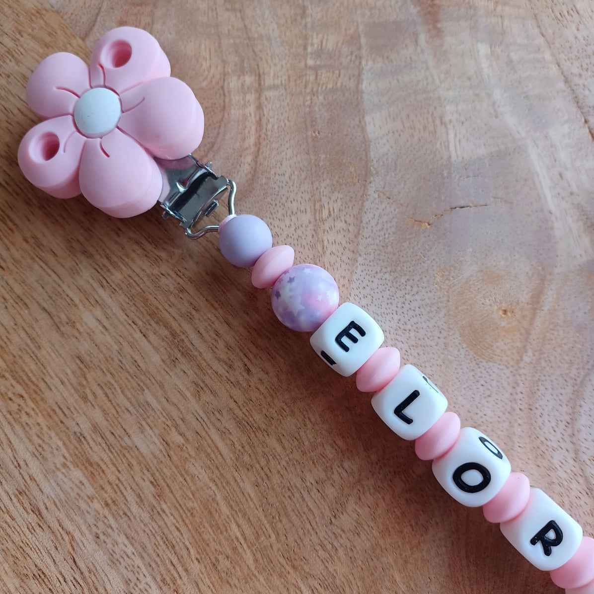 Attache tetine personnalisable, avec prénom du bébé ou enfant. Clip forme de fleur en silicone et acier inoxydable, perles du prénom en blanc et noir, perles rondes en lilas et rose pastel, perles de fleur . Cadeau de naissance