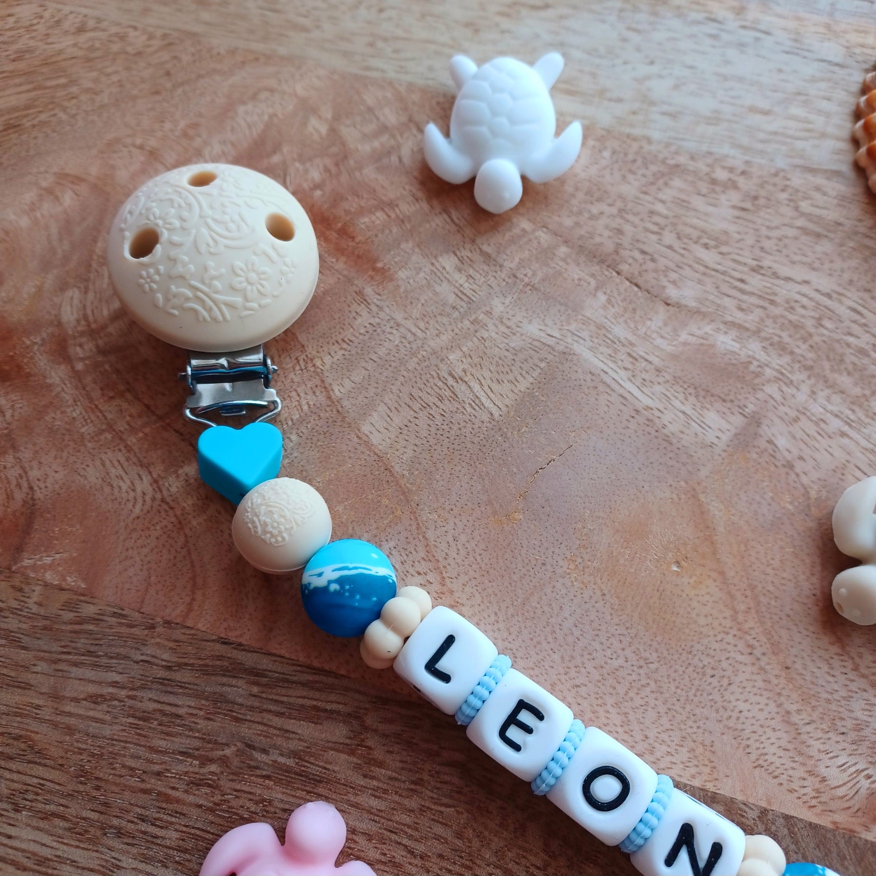 Attache tétine en silicone alimentaire, cadeau naissance, bébés, aux couleurs beige et bleu, perles imprimées en rappel aux bagues de la mer, coeur bleu marine, clip en silicone et acier inoxydable.