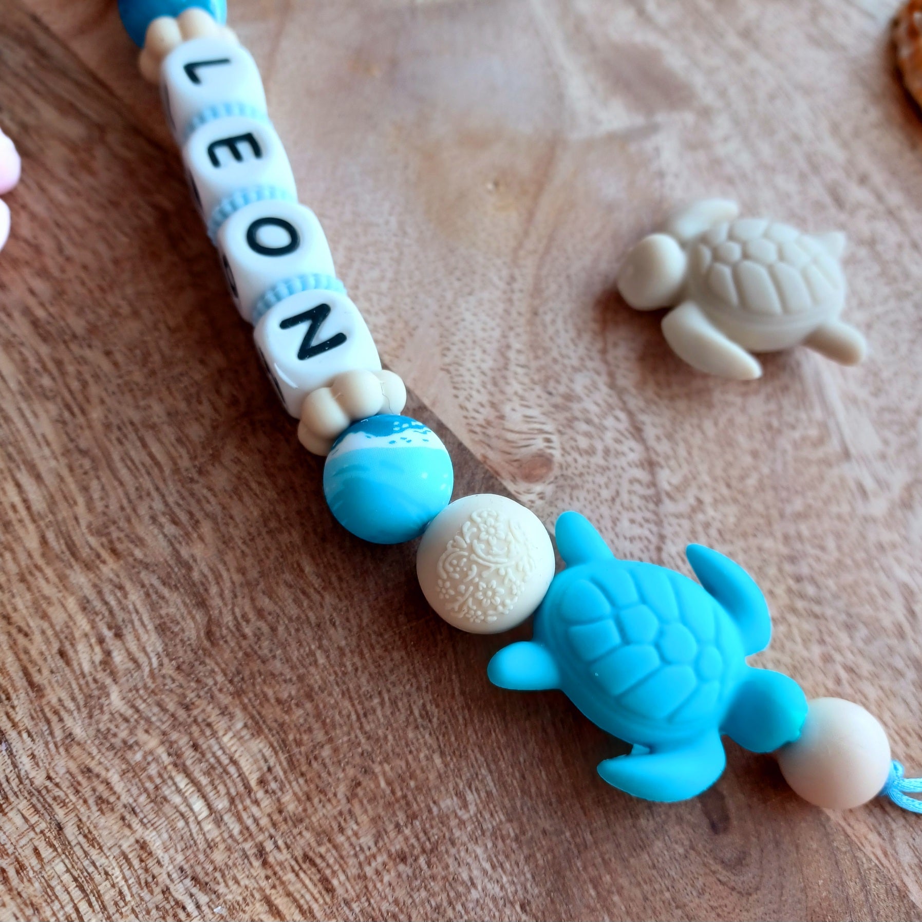 Attache tétine en silicone alimentaire, cadeau naissance, bébés, aux couleurs beige et bleu, perles imprimées en rappel aux bagues de la mer, coeur bleu marine, clip en silicone et acier inoxydable.