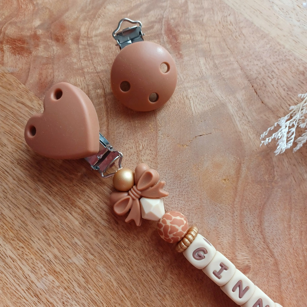 Attache tétine en silicone, personnalisable avec le prénom du bébé. Le clip est en silicone et acier inoxydable. Perles noeud et perles imprimées léopard. Superbe idée cadeau.