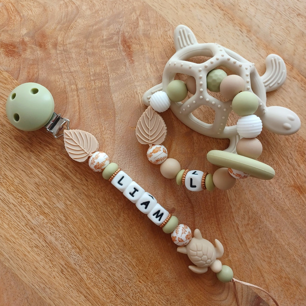 Attache tétine et anneau de dentition personnalisable en silicone alimentaire sans BPA, pour les bébés. Personnalisation avec prénom, perles ronds, fleuries, et perles ludiques en forme de feuilles et petits animaux (tortues, oiseaux, lions, safari, savane.