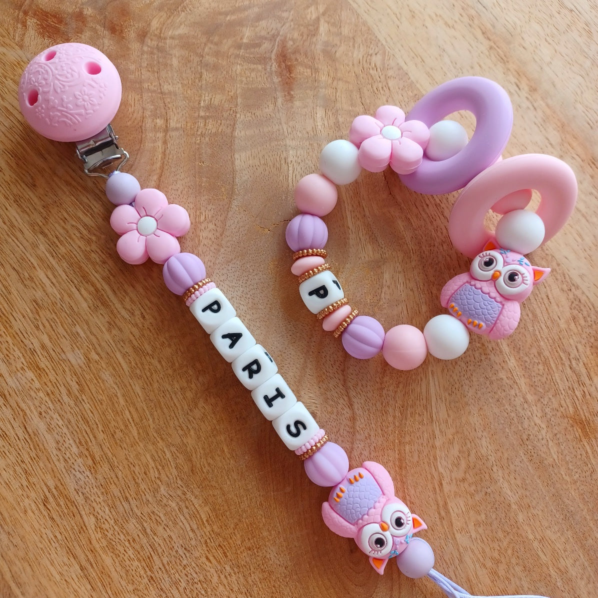 Attache tétine personnalisable en silicone alimentaire sans danger pour les bébés. Aux couleurs rose et lila, perles fleurs et hibou. Anneau de dentition avec des anneaux en silicone pour soulager les gencives des bébés. Superbe idée cadeau, babyshower, anniverssaire, baptême