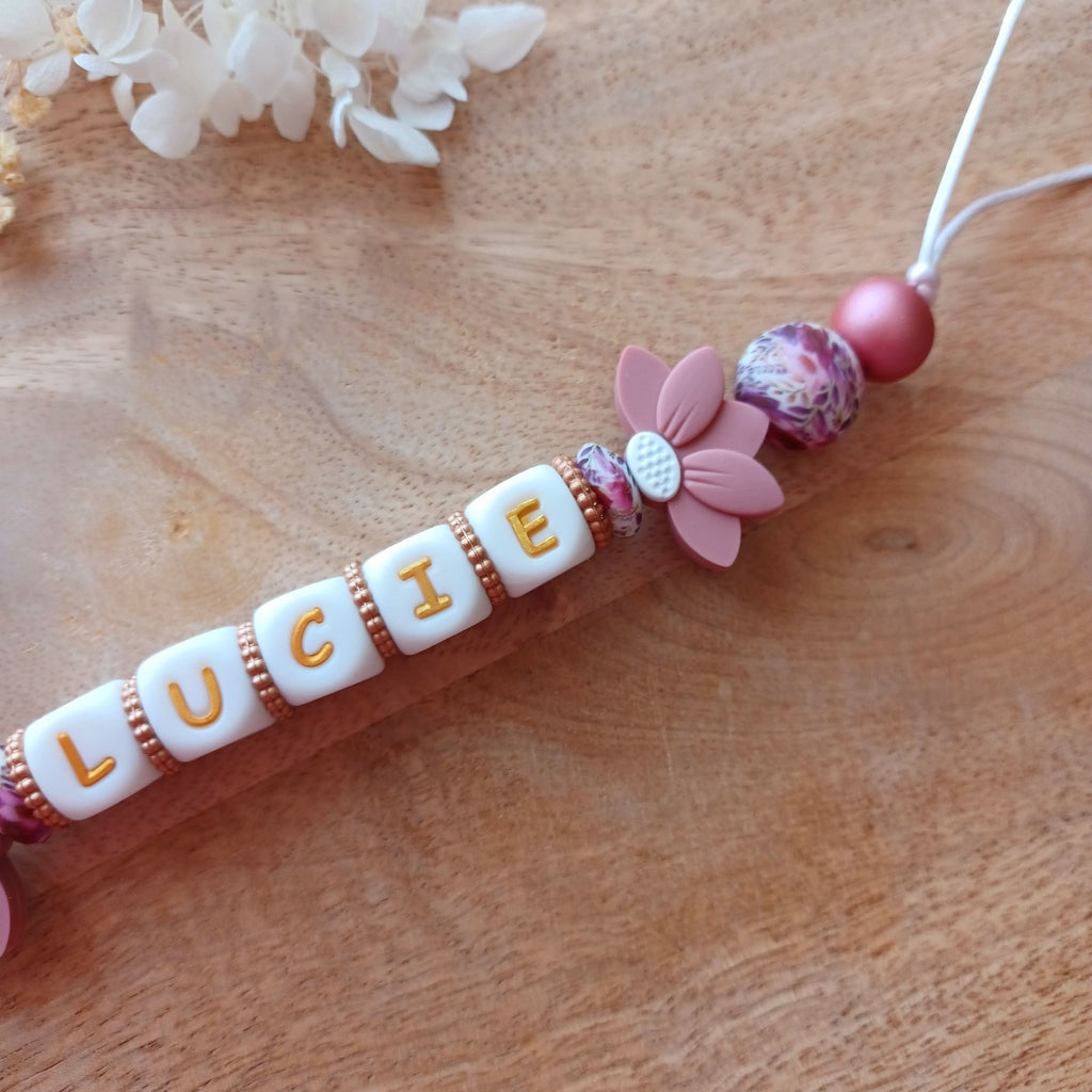 Attache tétine et anneau de dentition personnalisable avec le prénom du bébé. En silicone alimentaire sans bpa, clip robuste en acier inoxydable, perles imprimées, lettres blanche et dorées. Anneau de dentition pour soulager les dents de bébé