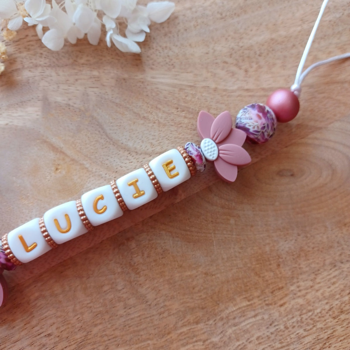 Attache tétine et anneau de dentition personnalisable avec le prénom du bébé. En silicone alimentaire sans bpa, clip robuste en acier inoxydable, perles imprimées, lettres blanche et dorées. Anneau de dentition pour soulager les dents de bébé