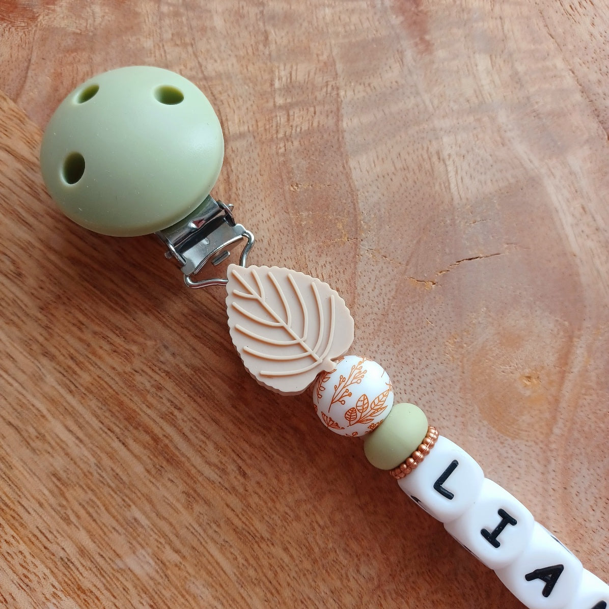 Attache tétine et anneau de dentition personnalisable en silicone alimentaire sans BPA, pour les bébés. Personnalisation avec prénom, perles ronds, fleuries, et perles ludiques en forme de feuilles et petits animaux (tortues, oiseaux, lions, safari, savane.