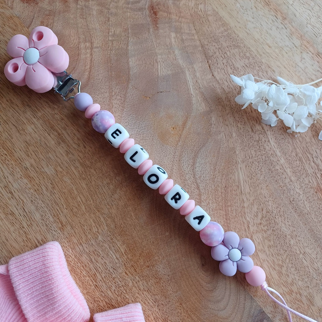 Attache tetine personnalisable, avec prénom du bébé ou enfant. Clip forme de fleur en silicone et acier inoxydable, perles du prénom en blanc et noir, perles rondes en lilas et rose pastel, perles de fleur . Cadeau de naissance