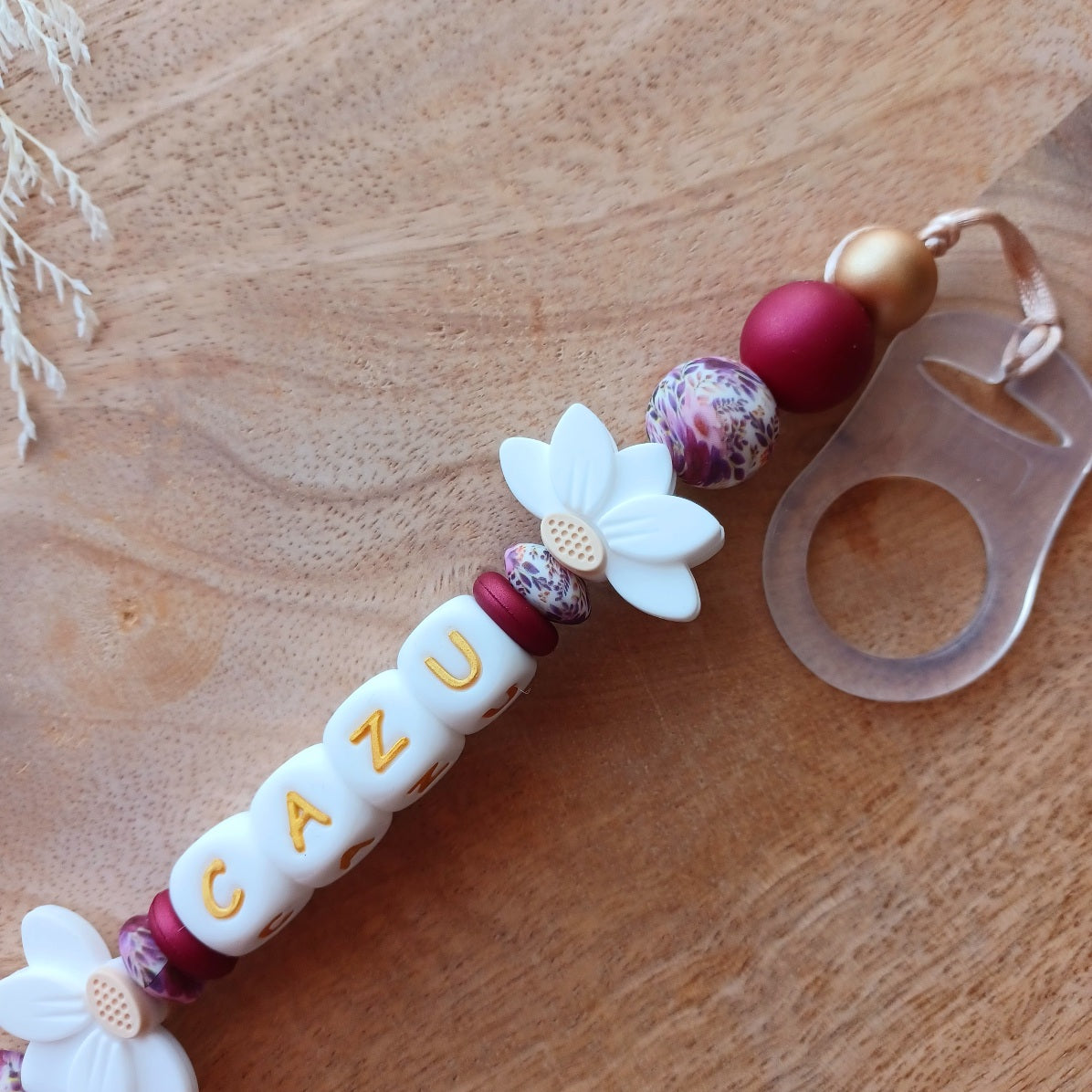 Attache tétine personnalisée en silicone avec prénom Cazu et fleurs blanches. Une attache tétine en silicone alimentaire sans bpa. Un anneau de dentition en silicone alimentaire, et cygne 