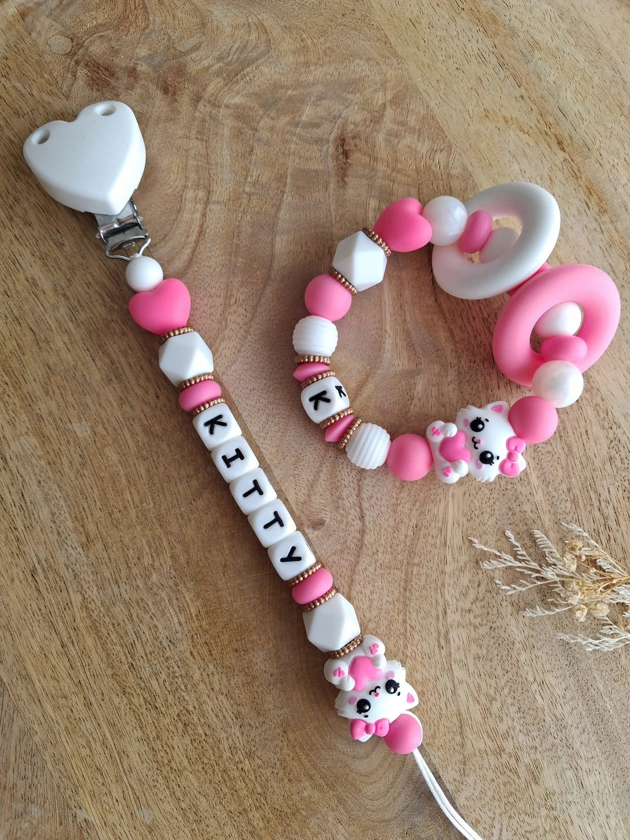 Attache tétine et anneau de dentition personnalisables en silicone alimentaire sans BPA. Aux couleurs blanc et rose fushia, perles rondes, ovales et hexagonales, anneau de dentition pour soulager les gencives de bébé. Cadeau de naissance.