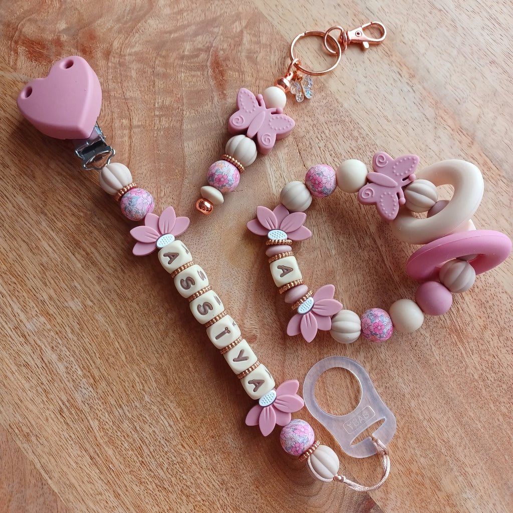 Attache tétine personnalisable avec le prénom de l'enfant, accompagné de son anneau de dentition assorti, en silicone alimentaire sans BPA. Aux couleurs vieux rose et beige
