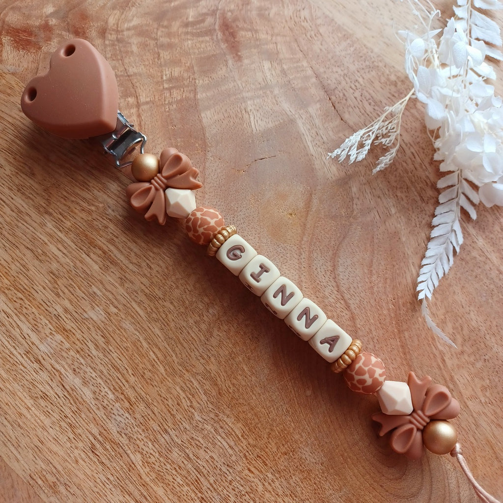 Attache tétine en silicone, personnalisable avec le prénom du bébé. Le clip est en silicone et acier inoxydable. Perles noeud et perles imprimées léopard. Superbe idée cadeau.