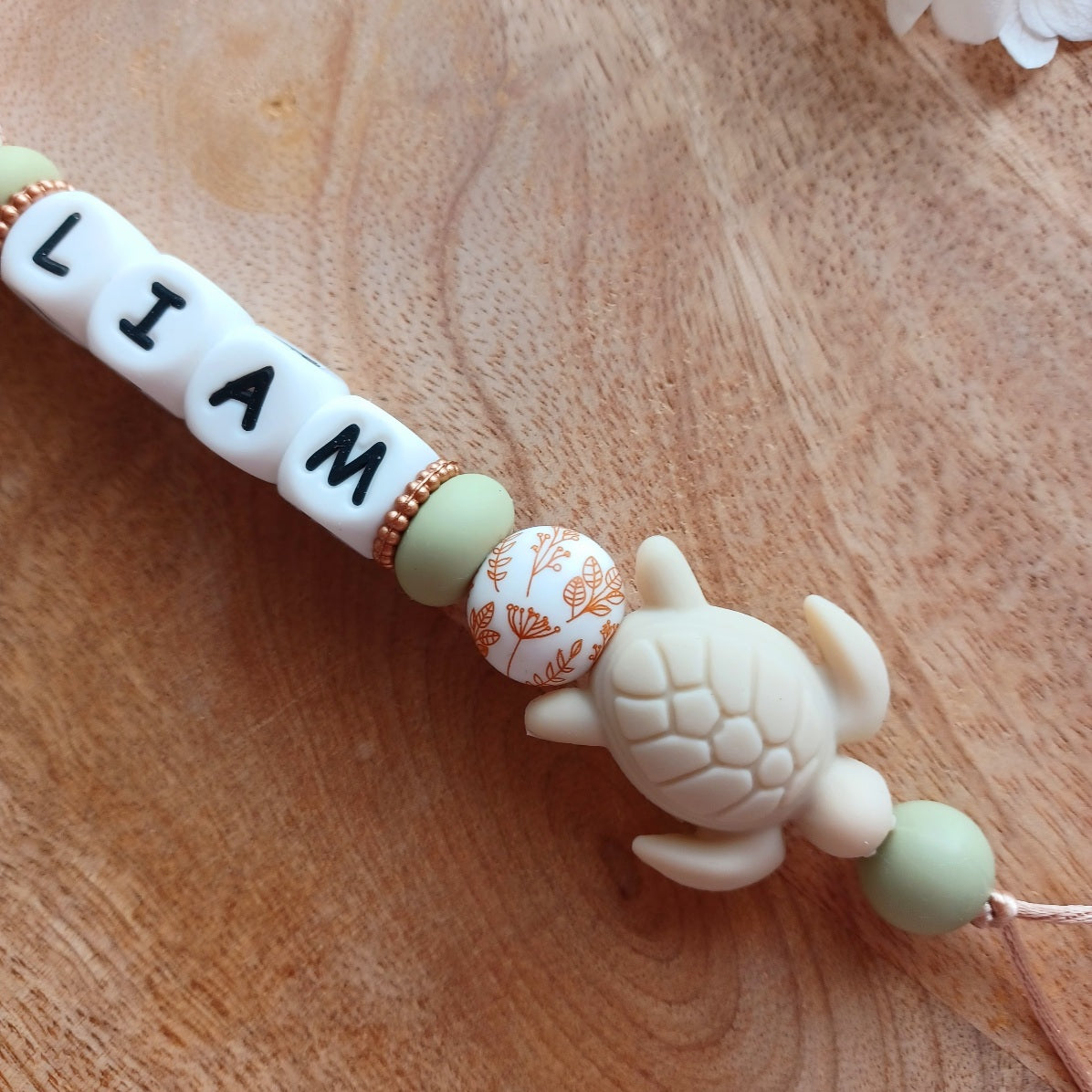 Attache tétine et anneau de dentition personnalisable en silicone alimentaire sans BPA, pour les bébés. Personnalisation avec prénom, perles ronds, fleuries, et perles ludiques en forme de feuilles et petits animaux (tortues, oiseaux, lions, safari, savane.