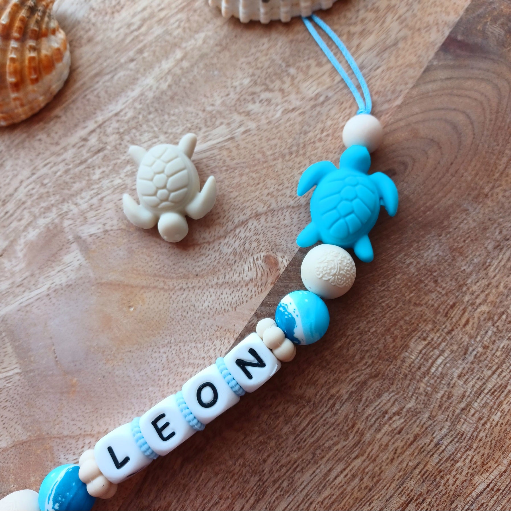 Attache tétine en silicone alimentaire, cadeau naissance, bébés, aux couleurs beige et bleu, perles imprimées en rappel aux bagues de la mer, coeur bleu marine, clip en silicone et acier inoxydable.