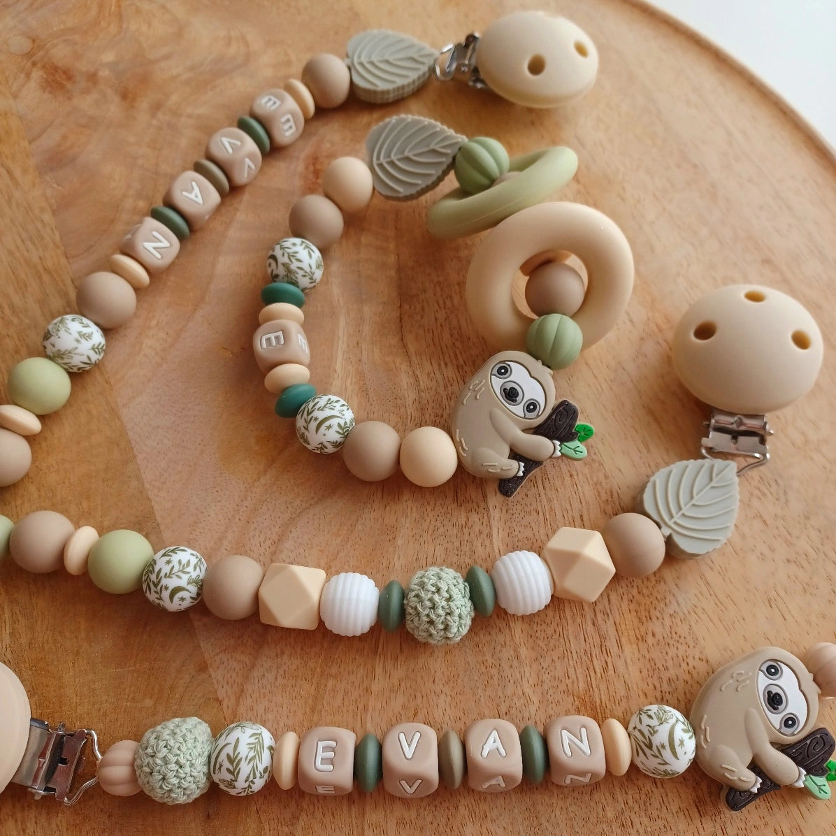 Ensemble cadeau de naissance composé de: attache tétine personnalisable, anneau de dentition, chaîne de poussette, ou et transat, aux couleurs vert, beige, taupe. Feuille et paresseux. Cadeau de naissance. 