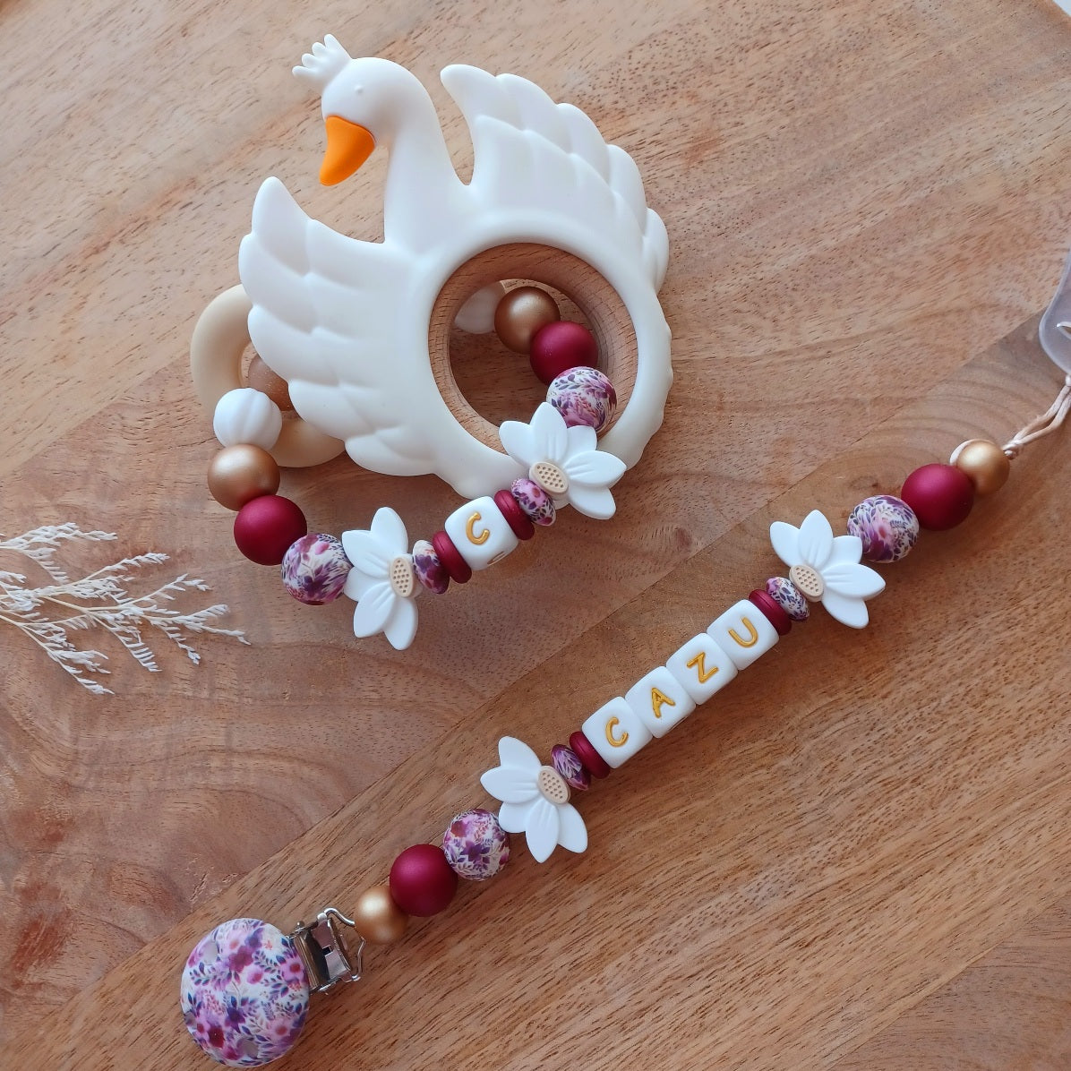 Attache tétine personnalisée en silicone avec prénom Cazu et fleurs blanches. Une attache tétine en silicone alimentaire sans bpa. Un anneau de dentition en silicone alimentaire, et cygne 