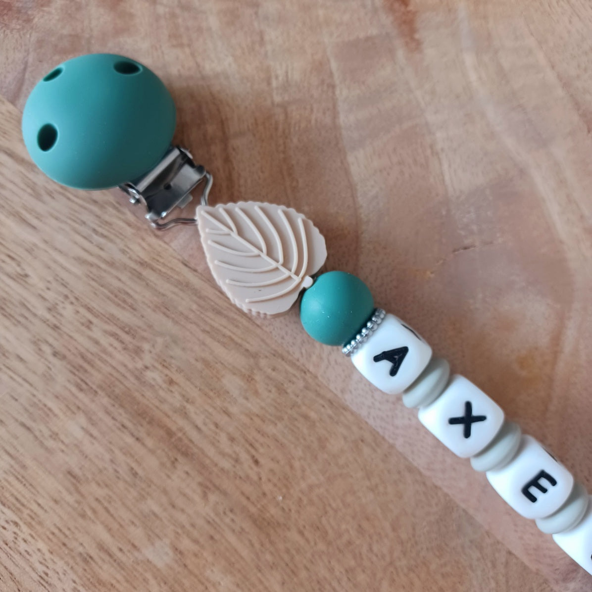 Attache tétine personnalisable en silicone alimentaire, aux couleurs vert-taupe. Clip en silicone et acier inoxydable. Idéal pour un cadeau naissance, nouveau-né.