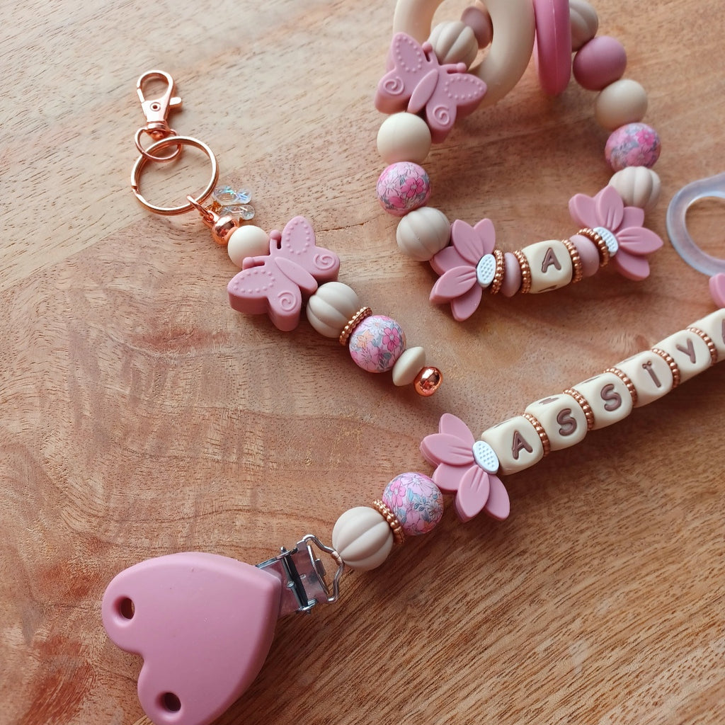 Attache tétine personnalisable avec le prénom de l'enfant, accompagné de son anneau de dentition assorti, en silicone alimentaire sans BPA. Aux couleurs vieux rose et beige